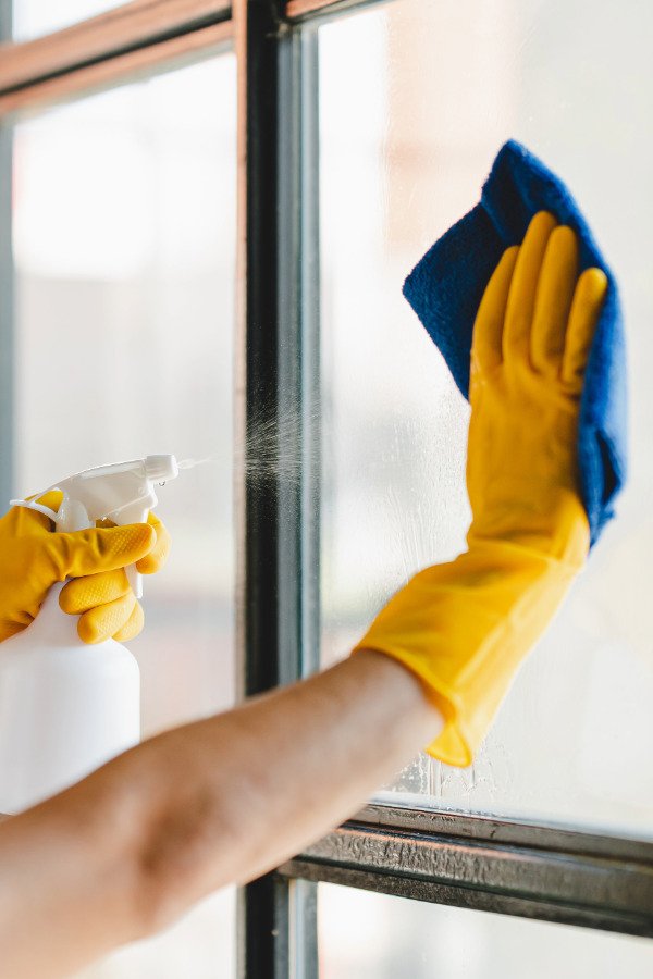 Professional cleaner cleaning windows in a home