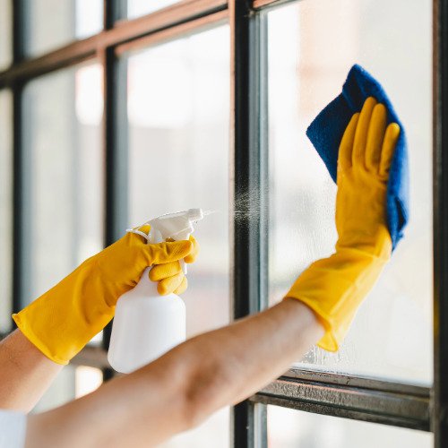 Professional cleaner cleaning windows in a home